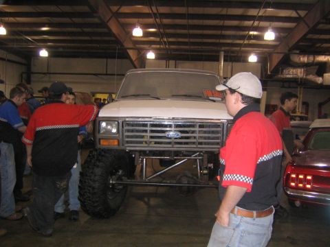 1982 Ford Bronco - Lifted white Ford truck with a chrome bar-style grille, blue Ford oval, oversized mud-terrain tires and a tube front bumper, photographed h…