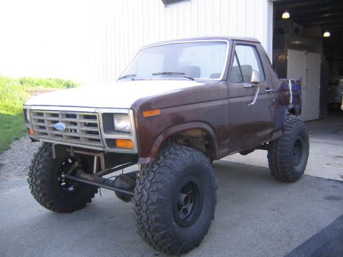 1982 Ford Bronco - This modified 1982 Ford Bronco features a significant lift and oversized tires, giving it an aggressive off-road stance.