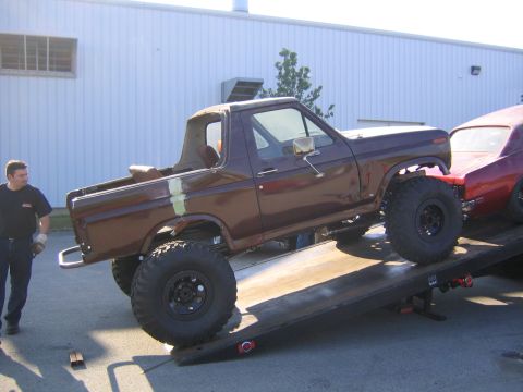 1982 Ford Bronco - A lifted brown Ford Bronco from the early 1980s is being towed on a flatbed truck.
