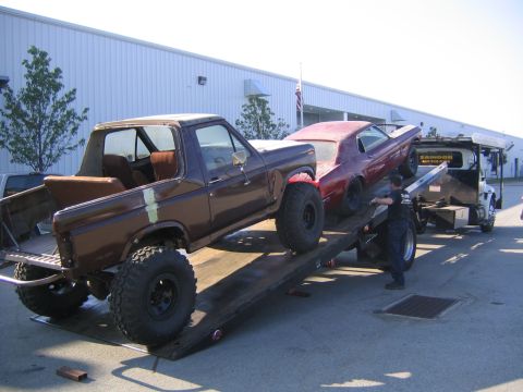 1982 Ford Bronco - A 1982 Ford Bronco and a red muscle car are being loaded onto a tow truck.