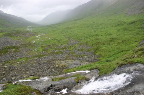 2003 Jeep TJ - A wide mountain valley landscape a stream flowing through green grass and rocky slopes.