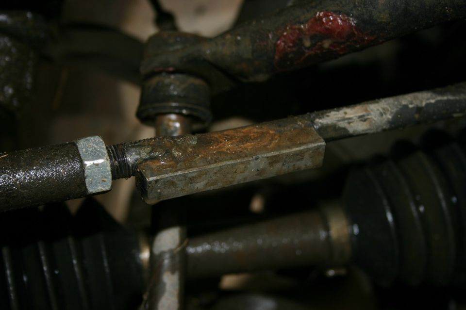 Rusty steering linkage with a hex-shaped adjustment sleeve and a rubber boot