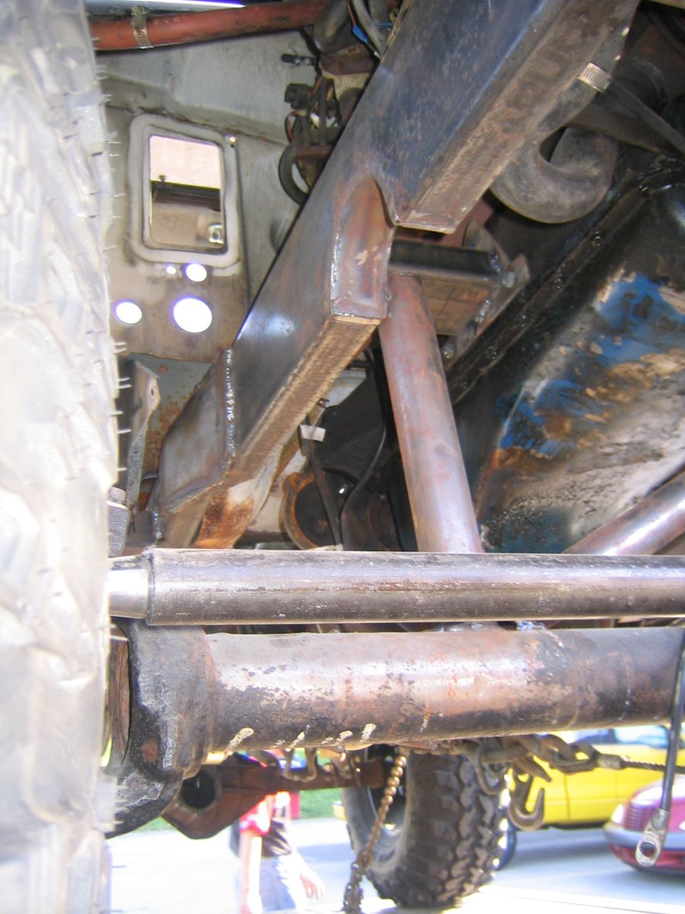 Close-up of rusty metal frame and suspension parts with a tire on the left