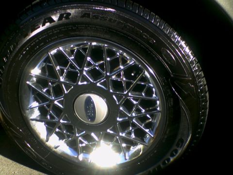 2001 Ford Crown Victoria - Chrome wire wheel and tire detail. Text on tire sidewall reads "YEAR ASSURANCE".