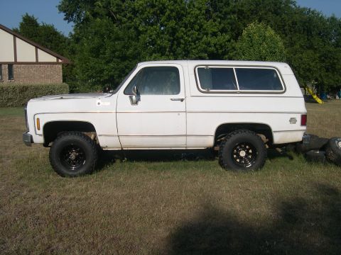 1980 Chevrolet Blazer - This white Chevrolet K5 Blazer from the 1970s is shown from the side with aftermarket wheels and a camper shell.