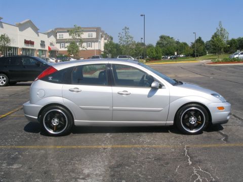 2003 Ford Focus - Silver hatchback with aftermarket rims parked in a lot.