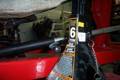 1995 Ford Taurus - A vehicle is supported by jack stands in a garage, with the engine compartment exposed for maintenance.