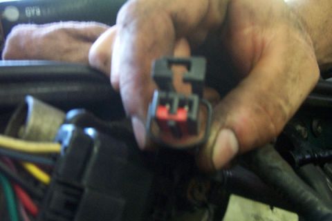1995 Ford Taurus - Close-up of a hand holding an electrical connector, likely during an engine repair or modification.