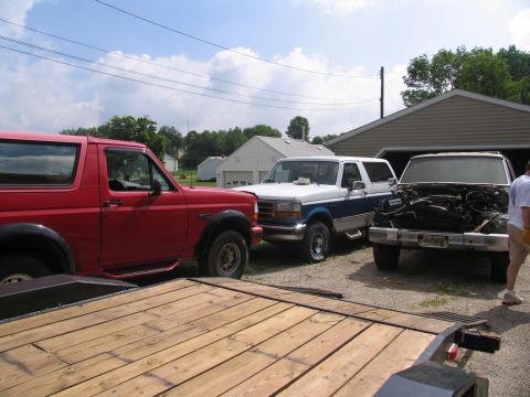 1986 Ford C-350 (Centurion Conversions) - Three trucks are parked in a driveway with a garage in the background.