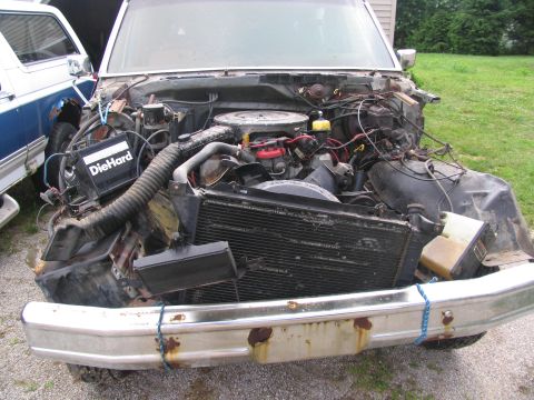 1986 Ford C-350 (Centurion Conversions) - Front end damage to a truck, exposing the engine and radiator. Another vehicle is parked nearby.