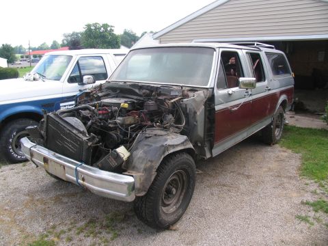 1986 Ford C-350 (Centurion Conversions) - This modified Ford Bronco, likely from the 1980s, is parked next to a pickup truck with its hood and front clip disassembled.