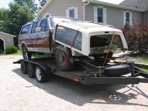1986 Ford C-350 (Centurion Conversions) - A two-tone Ford F-Series truck, likely from the 1980s, is transported on a trailer with its camper shell detached.