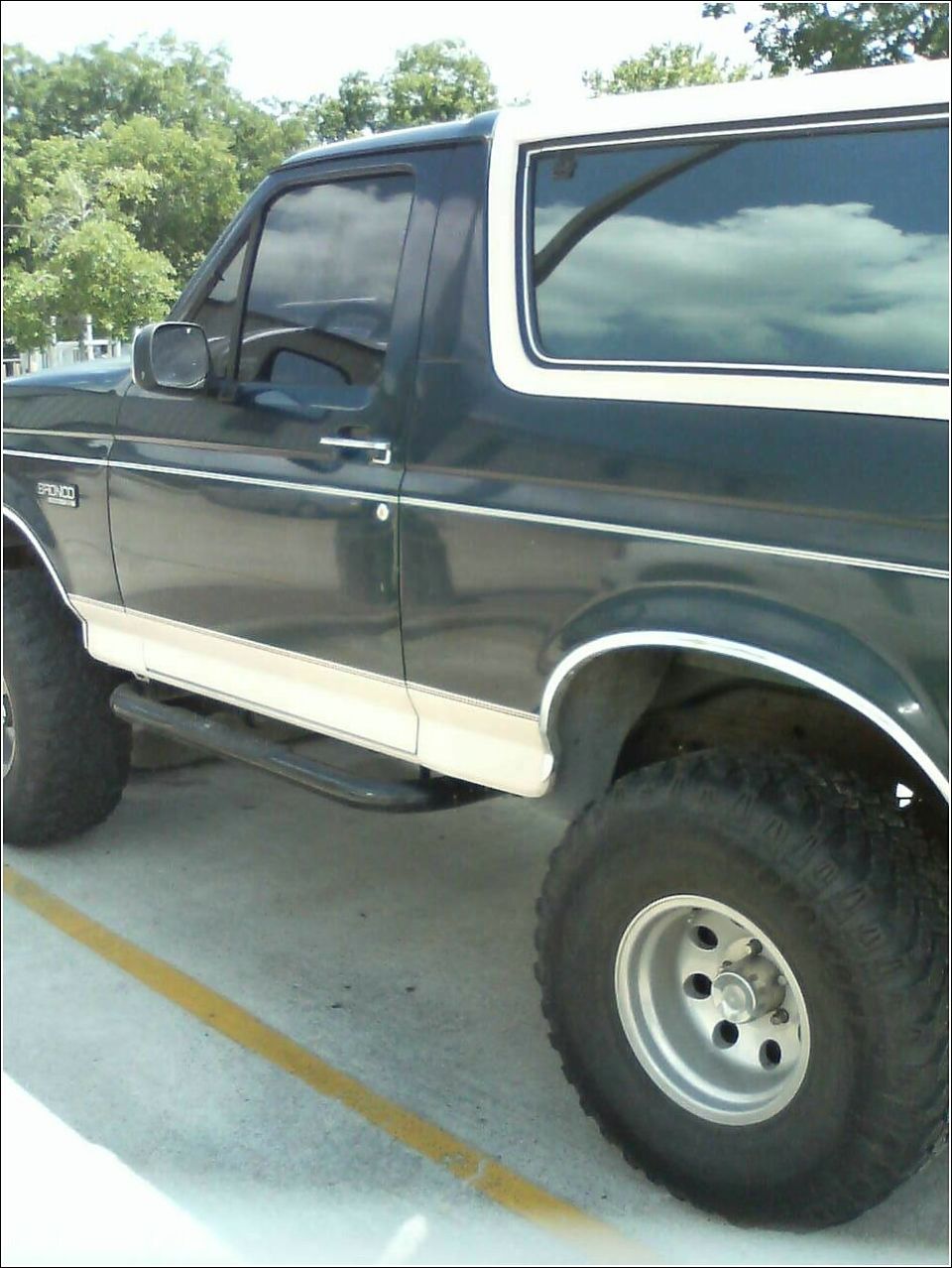 Dark green 1992 Ford Bronco with a white top, side view, showing running boards and aftermarket wheels