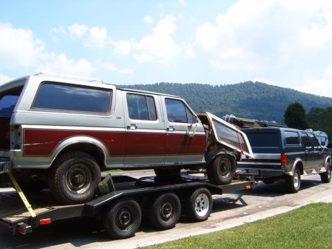 1993 Ford Bronco - Two SUVs are transported on trailers, one with a damaged door.