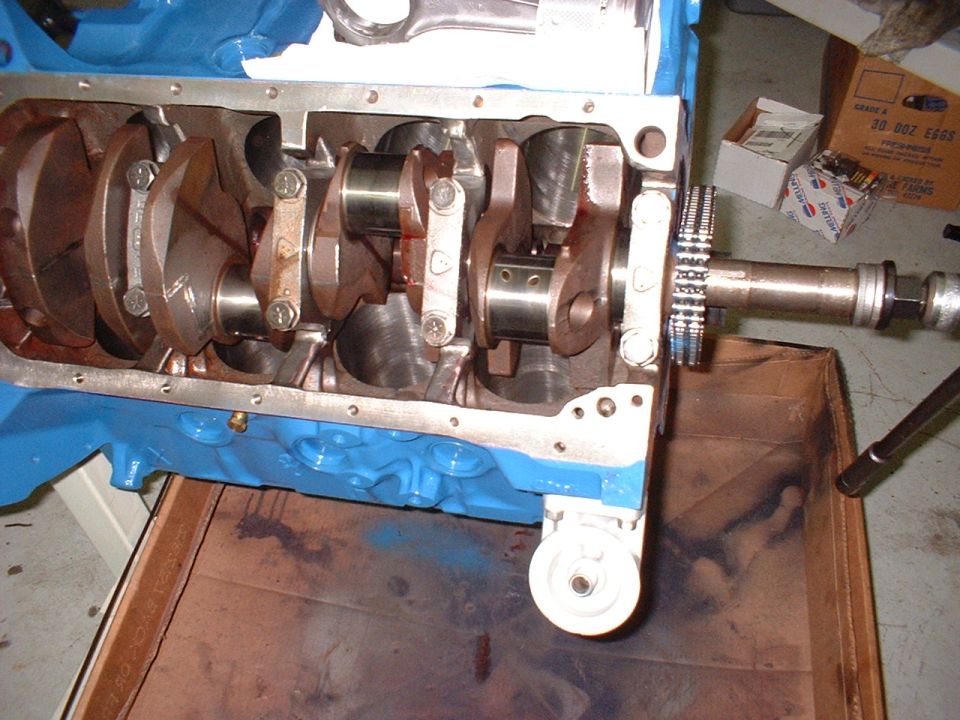 Engine block with crankshaft and connecting rods visible. A gear is attached to the front of the crankshaft
