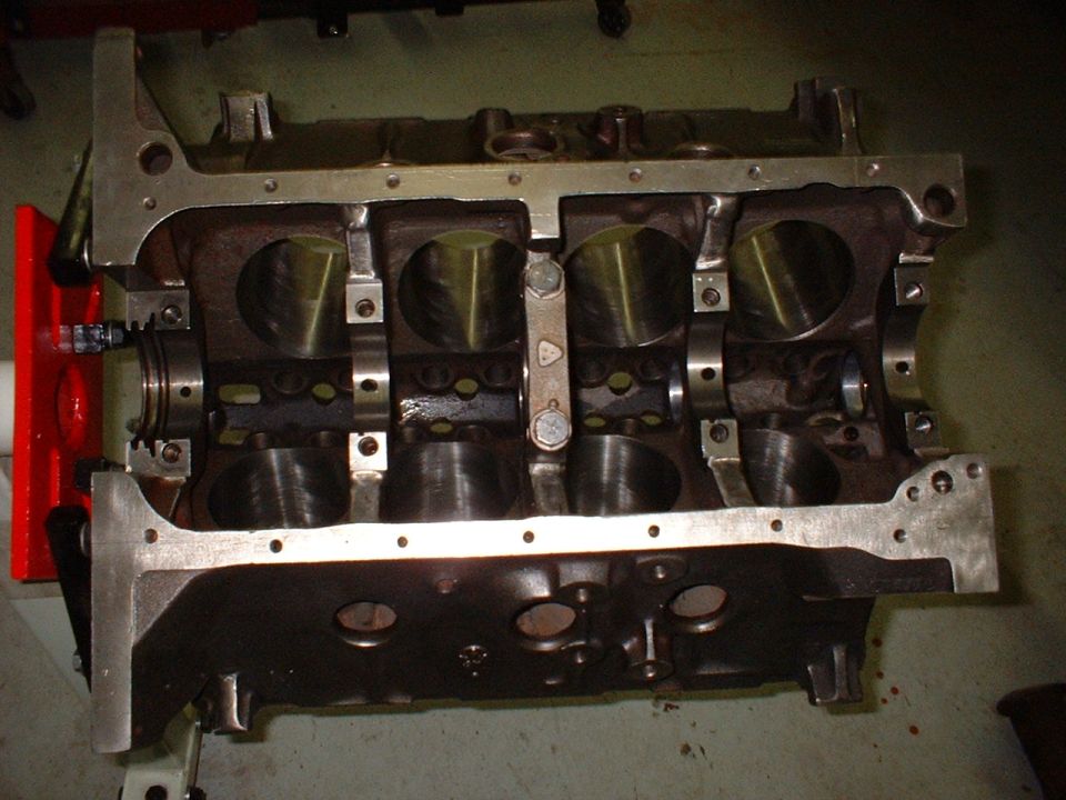 Bare V8 engine block on a stand, crankcase up, showing honed bores and main bearing caps
