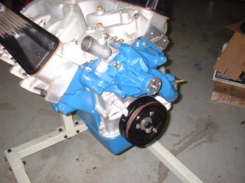 1965 Shelby Cobra - Close-up of an engine assembly, a blue water pump and a black pulley, mounted on a stand.