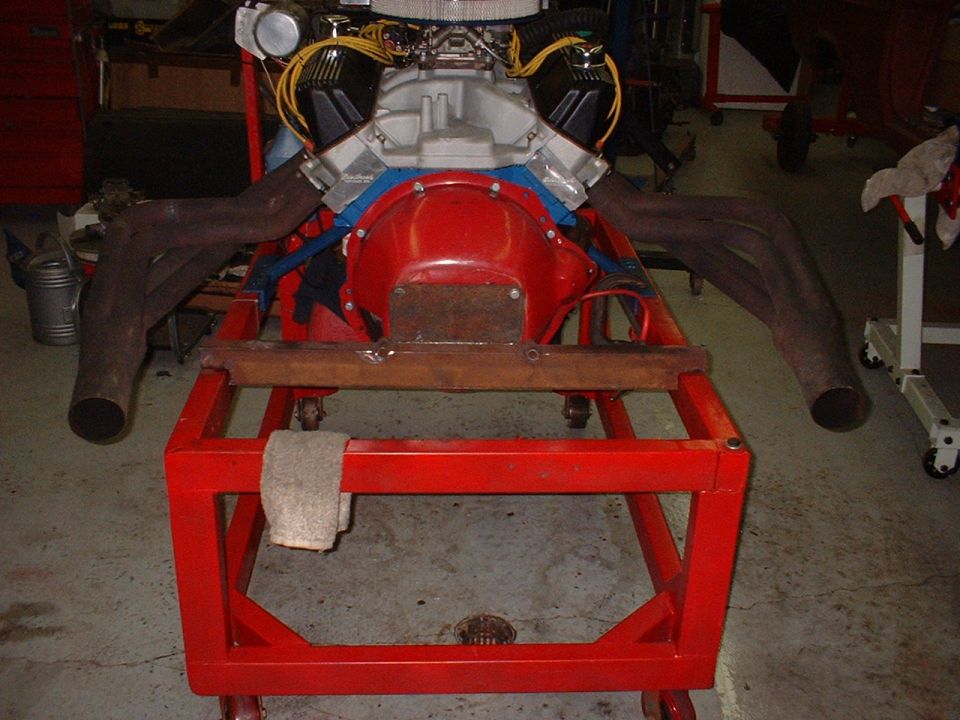V8 engine with dual exhaust manifolds on a red rolling stand