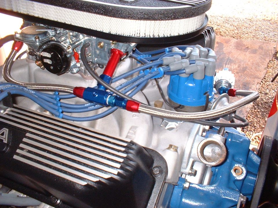 V8 engine with blue distributor, braided fuel lines, red/blue AN fittings and chrome carburetor