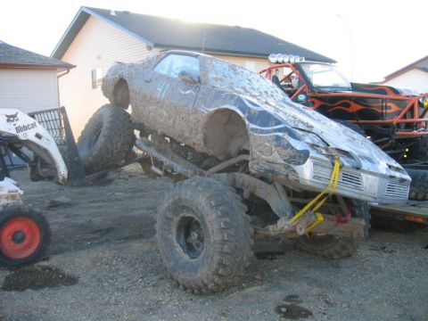 1995 Ford Bronco - A heavily modified vehicle, caked in mud, is shown with a Bobcat loader and another off-road vehicle nearby.
