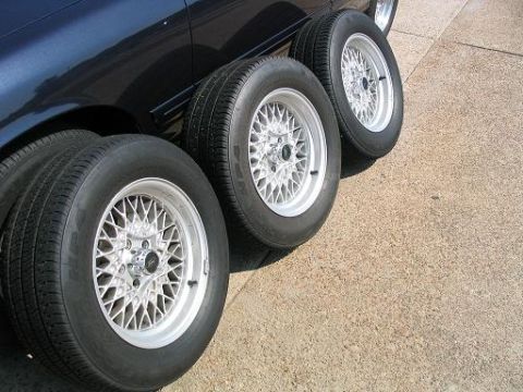 1999 Ford Crown Victoria - Aftermarket mesh rims and tires are displayed next to a dark blue vehicle.