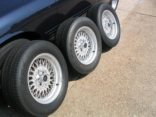 Four aftermarket mesh rims with tires on dark blue car body