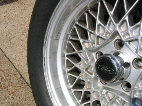 1999 Ford Crown Victoria - Close-up of a silver mesh wheel with a black Ford center cap and tire.