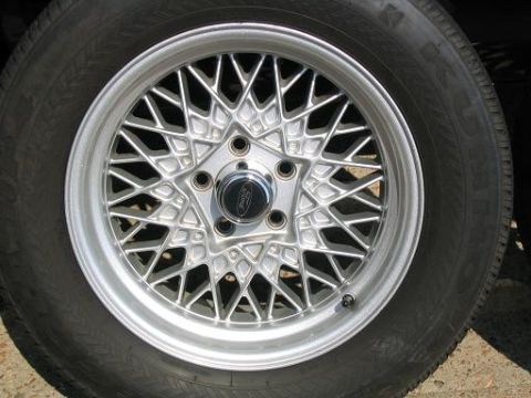 1999 Ford Crown Victoria - Close-up of a silver wire-spoke wheel with a Ford logo on the center cap.