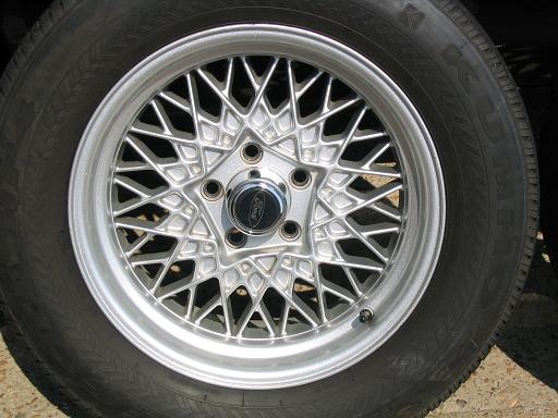 Silver wire-spoke wheel with a black Ford center cap and tire
