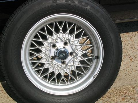 1999 Ford Crown Victoria - This is a close-up of a Ford wheel with a distinctive wire-spoke design.