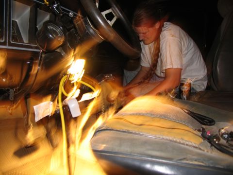 1978 Ford Bronco - Interior view of a vehicle with a person working on wiring under the dashboard.