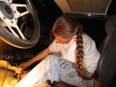 1978 Ford Bronco - A person works on the transmission inside a vehicle's interior.