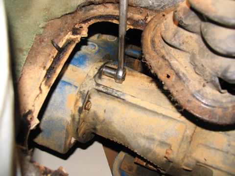 1978 Ford Bronco - Close-up of a transfer case with a wrench on a bolt, likely during removal or repair.