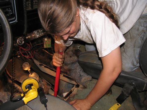 1978 Ford Bronco - A person is working on the interior of a vehicle, possibly removing parts from the floor near the transmission shifter.