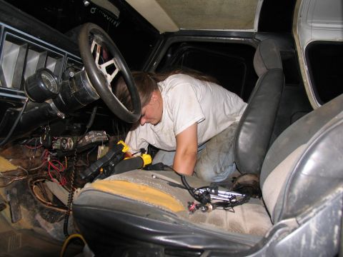 1978 Ford Bronco - A person is working on the interior wiring of a vehicle, possibly a truck or SUV.