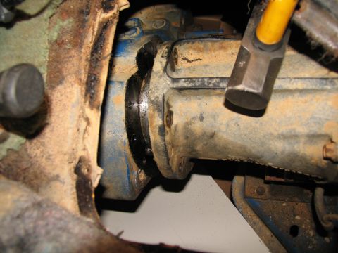 1978 Ford Bronco - Hammer poised over a vehicle's transfer case housing, suggesting an imminent repair or removal.