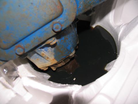 1978 Ford Bronco - Dark fluid collects around a vehicle's transfer case, suggesting a potential leak or maintenance issue.
