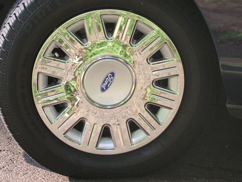 1999 Ford Crown Victoria - Close-up of a chrome wheel with the Ford emblem, consistent with a 1999 Crown Victoria.