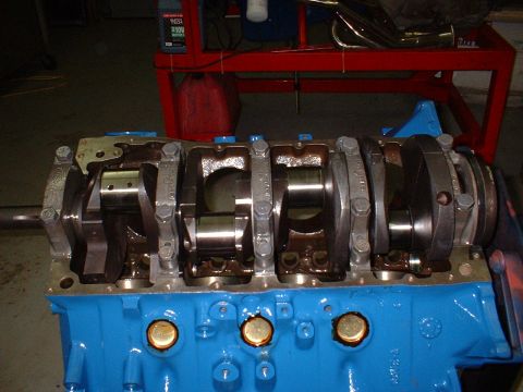 1970 Ford Torino - Close-up view of a blue engine block a crankshaft and connecting rods, with 'SUPERMOTORS' visible at the bottom.