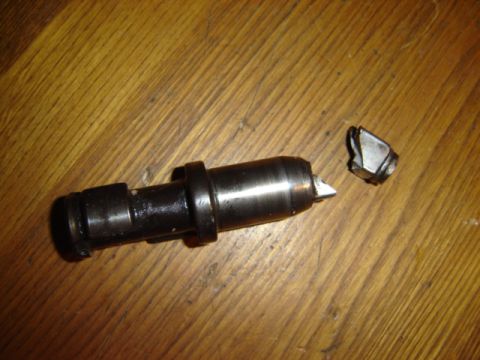 1992 Ford Bronco - A broken valve stem and rocker arm lie on a wooden surface, indicating engine damage.
