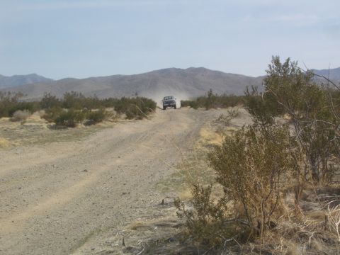 1985 Ford Ranger - A truck navigates a dirt road through a dry, arid landscape under a clear sky.