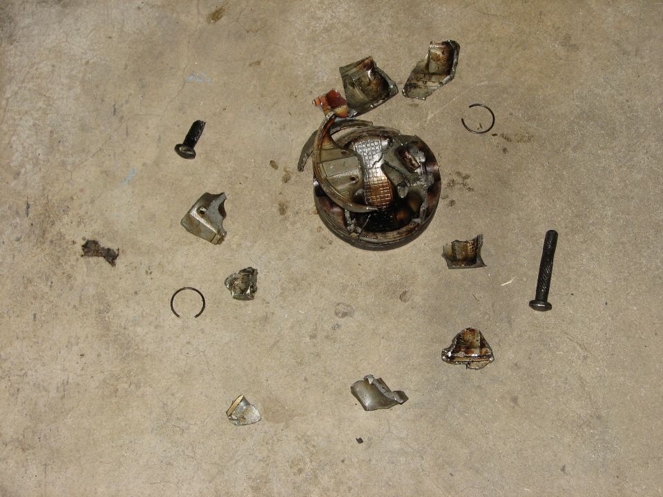 Blown engine piston and connecting rod fragments scattered on concrete floor
