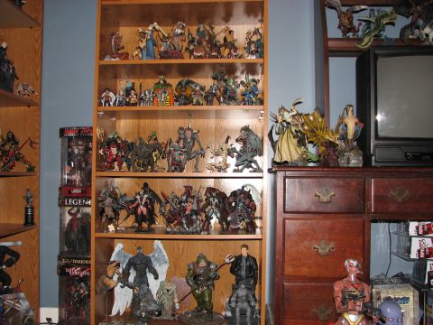 1991 Ford Bronco - A collection of action figures and fantasy statues are displayed on wooden shelves in a room.