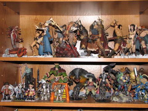 1991 Ford Bronco - A collection of fantasy and action figures are organized on two shelves within a wooden display unit.