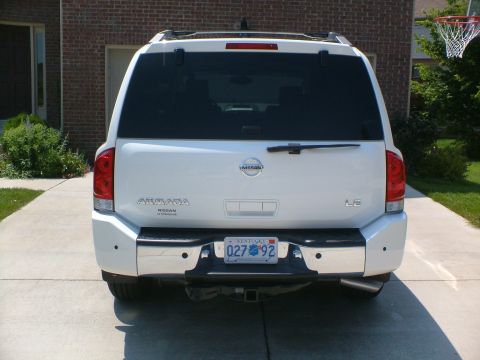 2006 Nissan Armada - The rear of a white Nissan Armada SUV is parked in a driveway in front of a brick house.