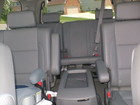 2006 Nissan Armada - The interior of a vehicle shows multiple rows of gray leather seats and a center console.