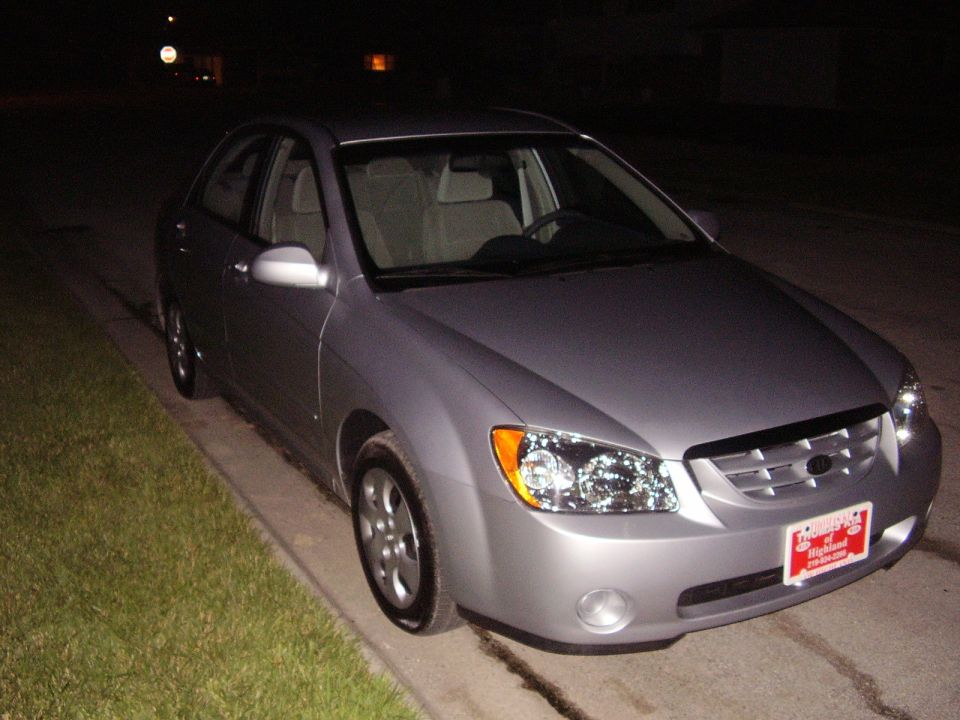 Silver sedan parked on the side of the road at night. License plate is visible