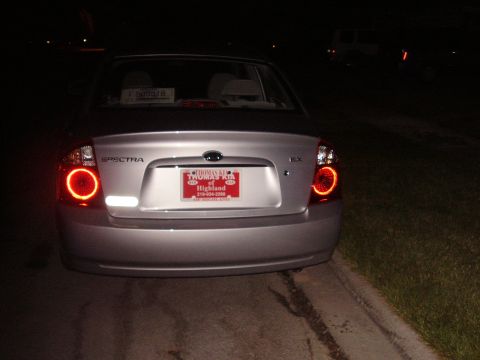 1996 Ford F-150 - The rear of a silver sedan is visible at night, illuminated taillights and a license plate frame from a dealership.