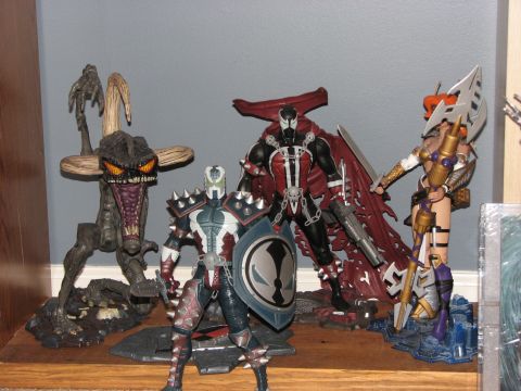 1991 Ford Bronco - A collection of Spawn action figures, including a monster, a warrior, and a central figure with a cape, are displayed on a shelf.