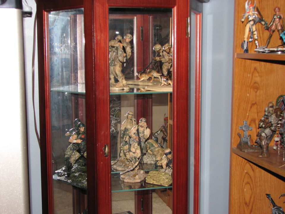 Display cabinet with shelves holding military action figures, some with dogs